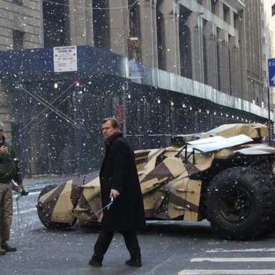 Christopher Nolan junto al batpod de camuflaje