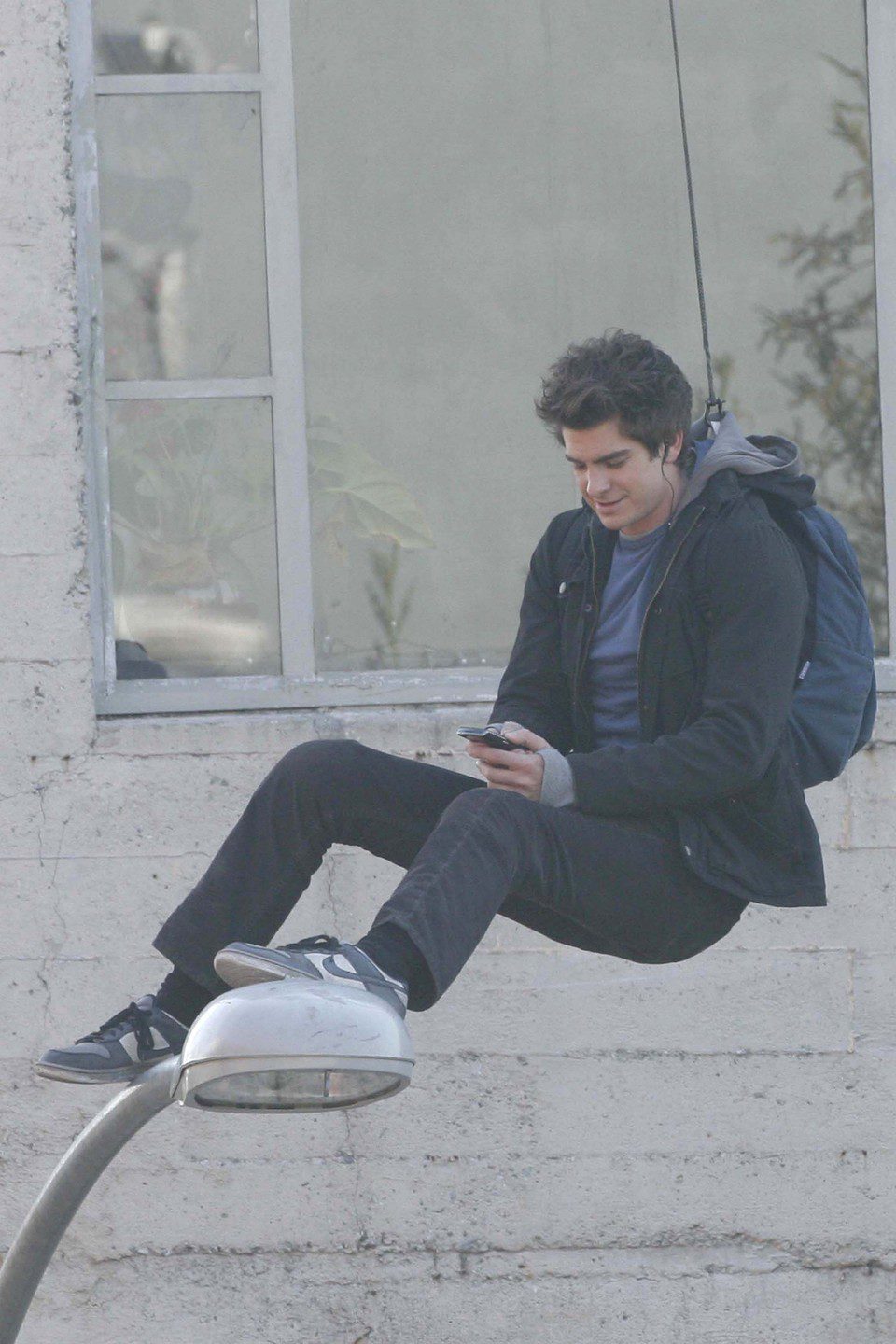 Andrew Garfield usa el móvil subido en una farola en el set de 'The Amazing Spider-Man'